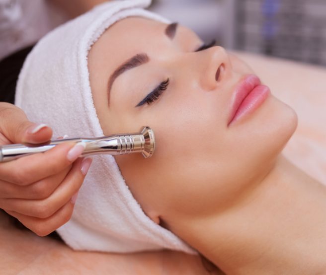 The doctor-cosmetologist makes the procedure Microdermabrasion of the facial skin of a beautiful, young woman in a beauty salon.Cosmetology and professional skin care.